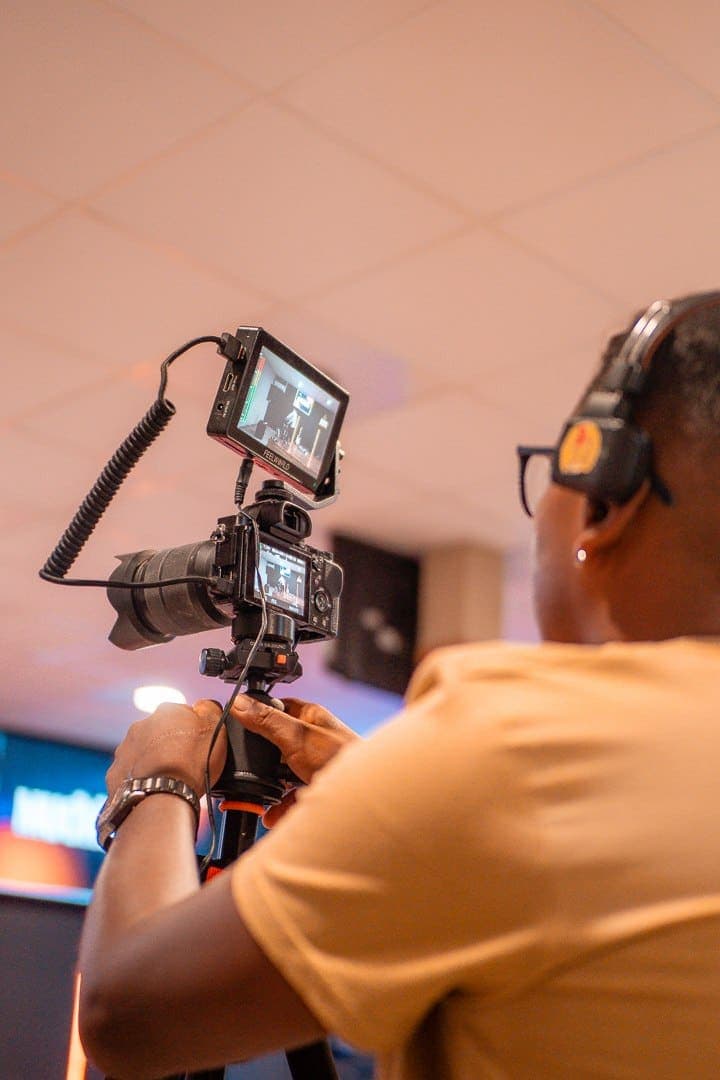 Un cámara del equipo audiovisual grabando el servicio con una cámara sobre trípode