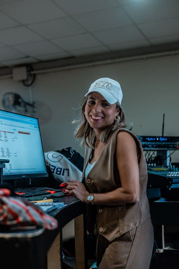 Una voluntaria del equipo de producción sonriendo junto al ordenador de la mesa de control