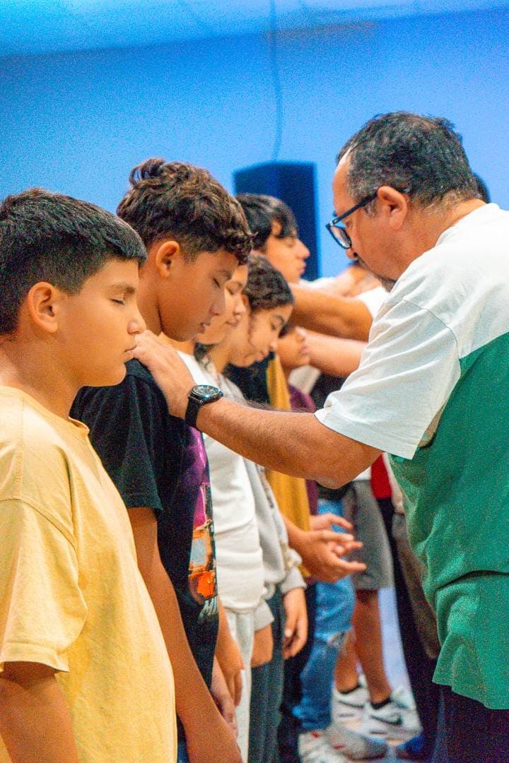 Un pastor imponiendo las manos sobre los jóvenes, en oración, durante la ministración