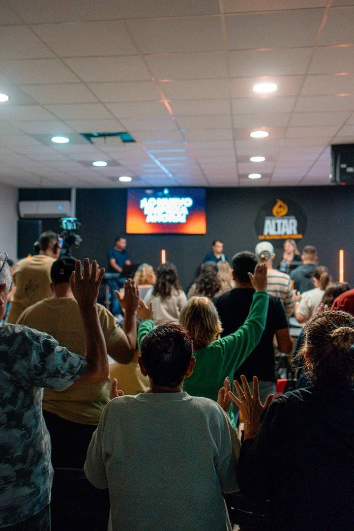La sala de espaldas, con las manos levantadas, mientras los invitados ministran desde la tarima