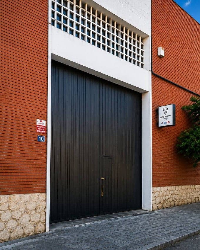 La entrada de la iglesia: un portón negro entre ladrillo rojo, con el cartel de Vida Nueva Reus a la derecha